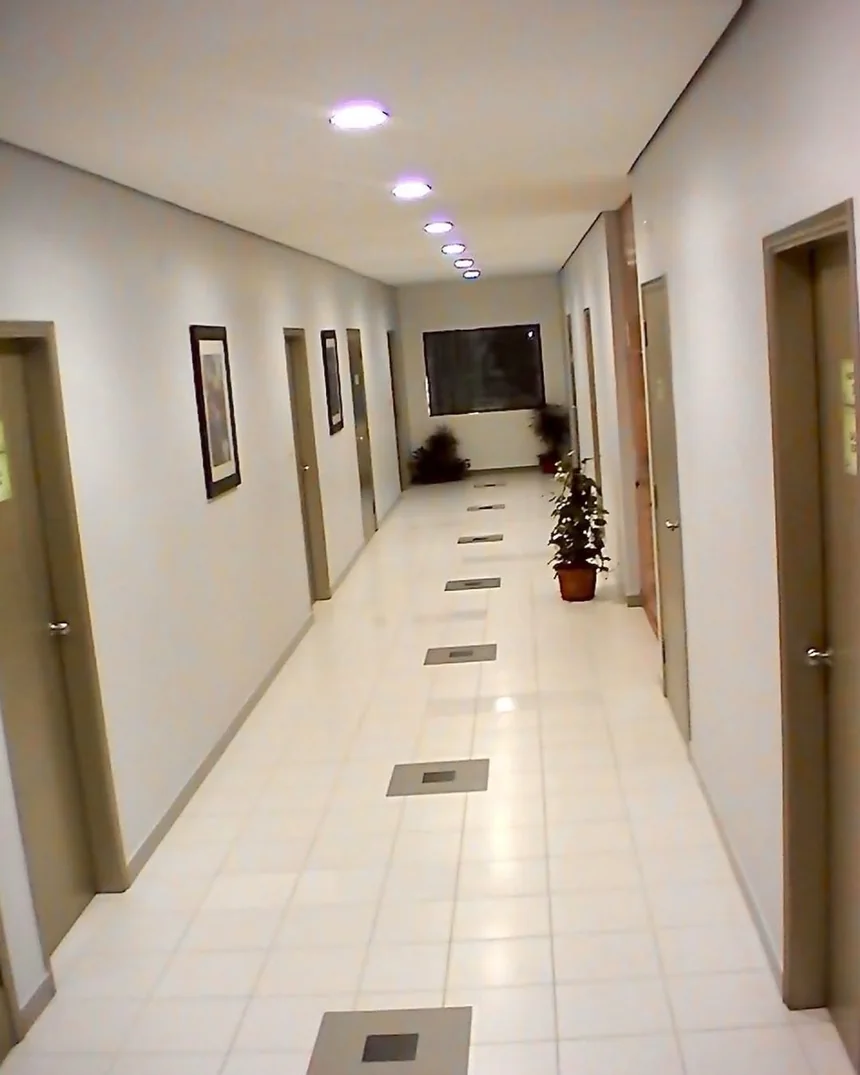 Pasillo de oficinas corporativas con luces embutidas